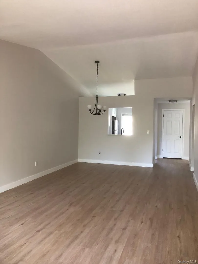 Spacious, open living/dining room featuring vaulted ceilings, a contemporary chandelier, and wood-like flooring Spacious, open living/dining room featuring vaulted ceilings, a contemporary chandelier, and wood-like flooring