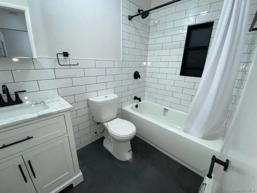 Beautifully renovaterd bathromm featuring white subway tile surround with dark grout, built-in black shower niche, matte black shower fixtures, and a white bathtub Beautifully renovaterd bathromm featuring white subway tile surround with dark grout, built-in black shower niche, matte black shower fixtures, and a white bathtub