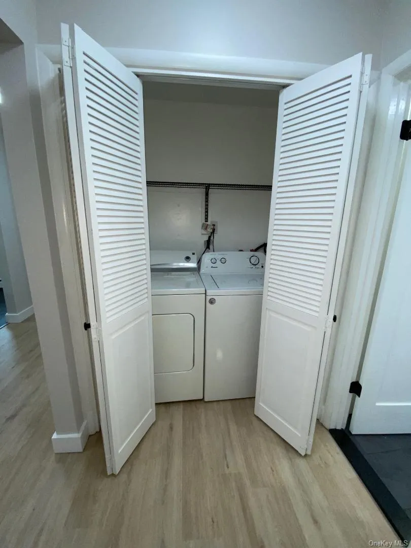 Dedicated laundry closet featuring louvered bi-fold doors, a full size washer and dryer, and a wire storage shelf. Dedicated laundry closet featuring louvered bi-fold doors, a full size washer and dryer, and a wire storage shelf.