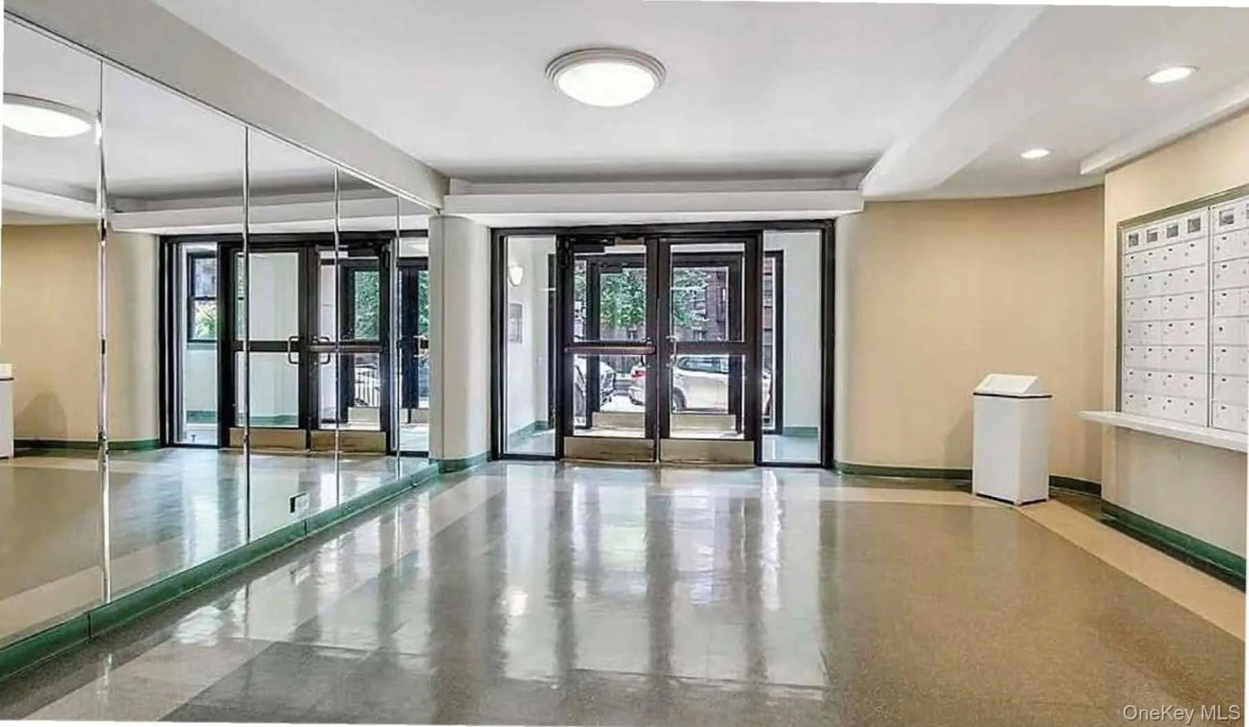 Polished flooring, full-height mirrored wall, multi-panel glass entry doors, recessed lighting, and wall-mounted mailboxes Polished flooring, full-height mirrored wall, multi-panel glass entry doors, recessed lighting, and wall-mounted mailboxes