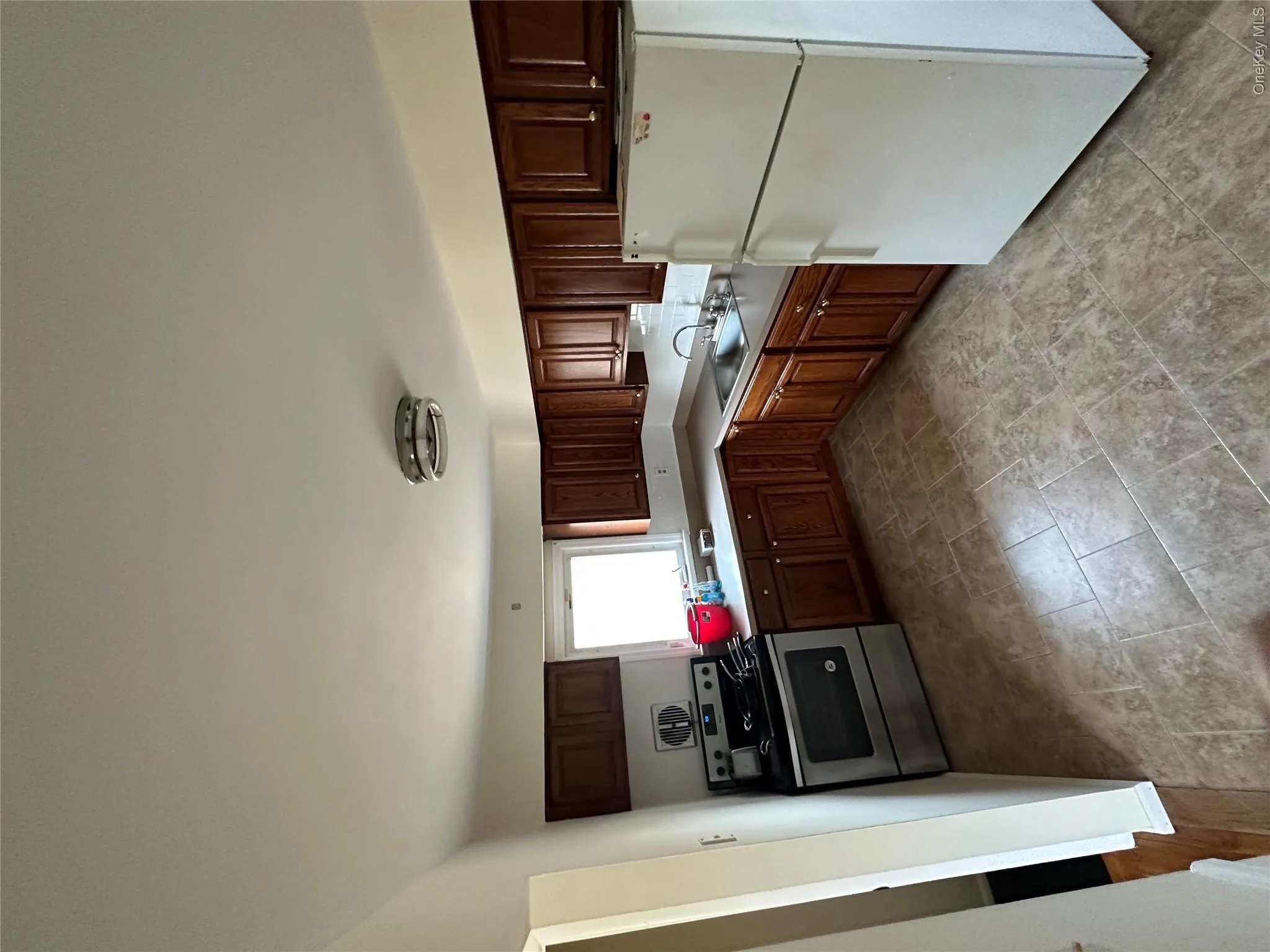 Kitchen featuring wood-finish cabinetry, stainless steel range, and a window Kitchen featuring wood-finish cabinetry, stainless steel range, and a window