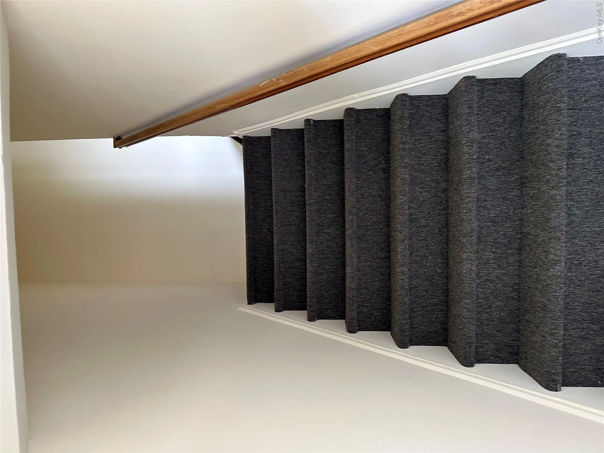 Carpeted staircase with a wood handrail Carpeted staircase with a wood handrail
