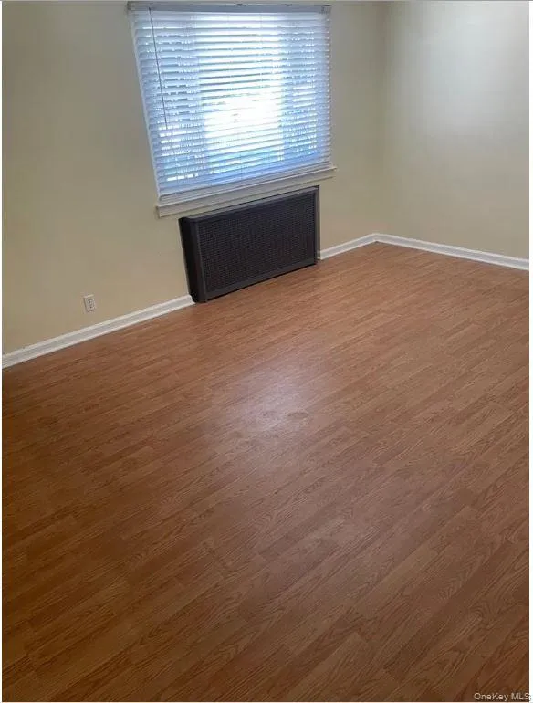 Unfurnished room with radiator heating unit and wood finished floors Unfurnished room with radiator heating unit and wood finished floors