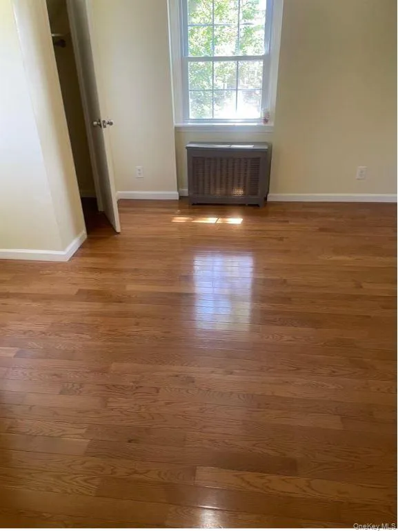 Unfurnished bedroom featuring radiator and wood finished floors Unfurnished bedroom featuring radiator and wood finished floors