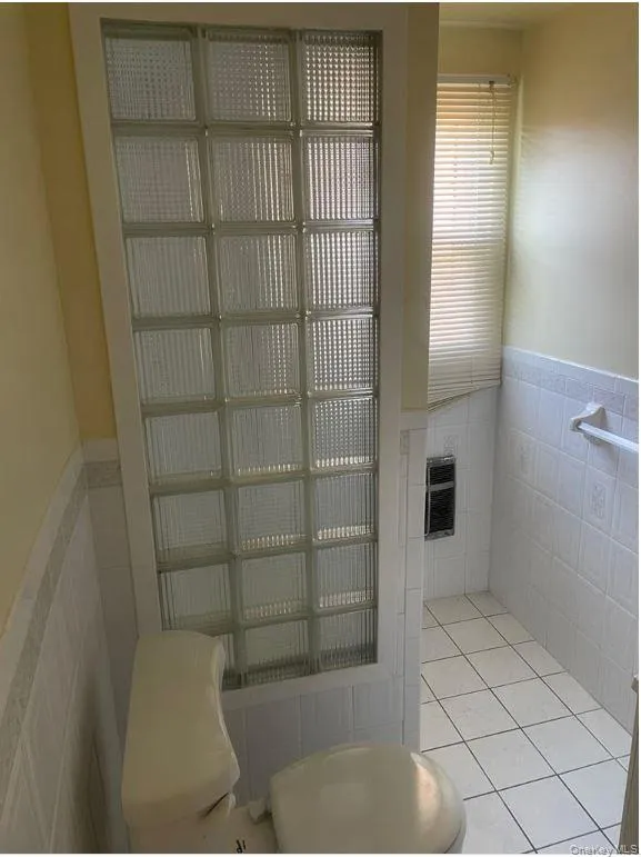 Bathroom with tile walls, a wainscoted wall, heating unit, tile patterned flooring, and a fireplace Bathroom with tile walls, a wainscoted wall, heating unit, tile patterned flooring, and a fireplace