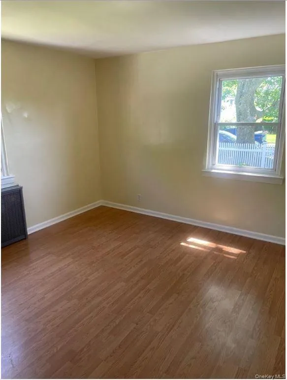 Spare room featuring dark wood-style floors and radiator heating unit Spare room featuring dark wood-style floors and radiator heating unit