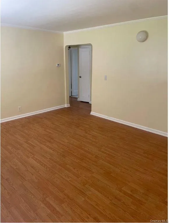 Empty room featuring ornamental molding and wood finished floors Empty room featuring ornamental molding and wood finished floors