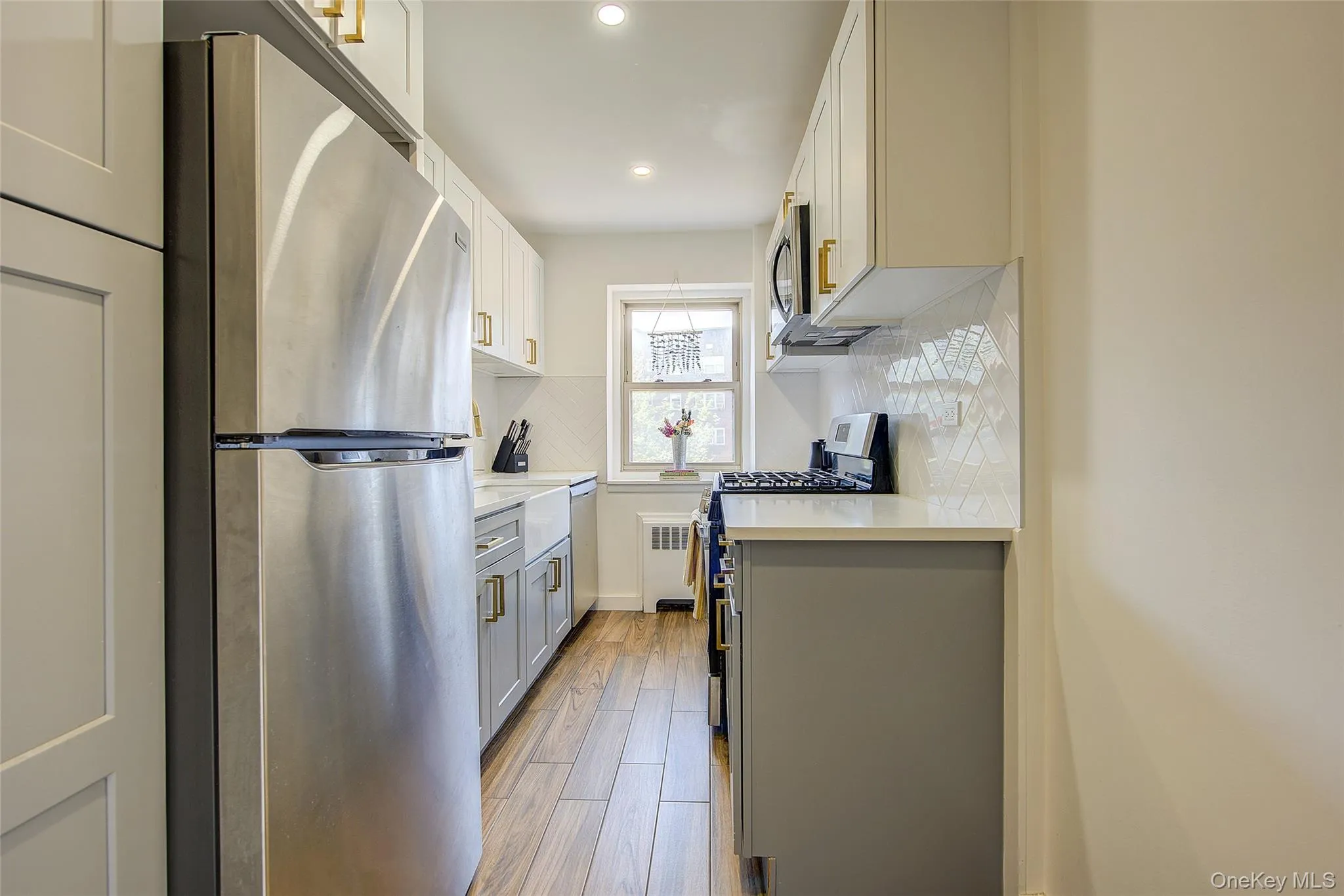 Kitchen with appliances with stainless steel finishes, gray cabinets, light countertops, recessed lighting, and decorative backsplash Kitchen with appliances with stainless steel finishes, gray cabinets, light countertops, recessed lighting, and decorative backsplash