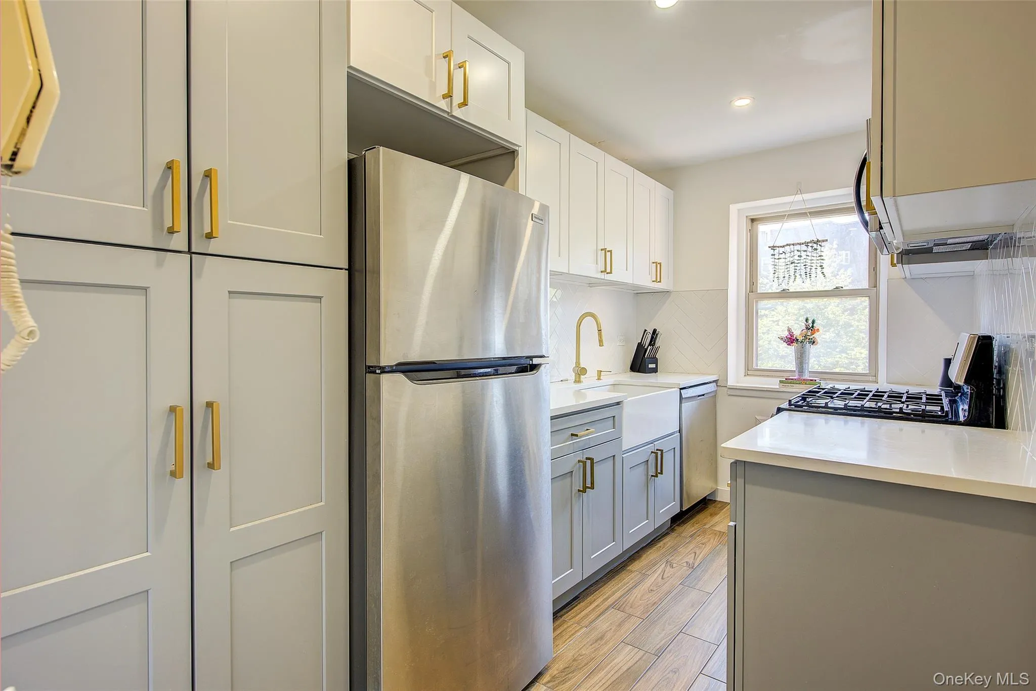 Kitchen with stainless steel appliances, light countertops, recessed lighting, gray cabinetry, and light wood-style flooring Kitchen with stainless steel appliances, light countertops, recessed lighting, gray cabinetry, and light wood-style flooring