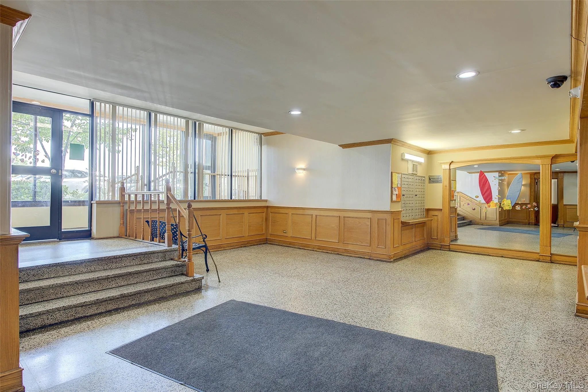 Building lobby featuring a decorative wall, wainscoting, stairway, a security system, and recessed lighting Building lobby featuring a decorative wall, wainscoting, stairway, a security system, and recessed lighting
