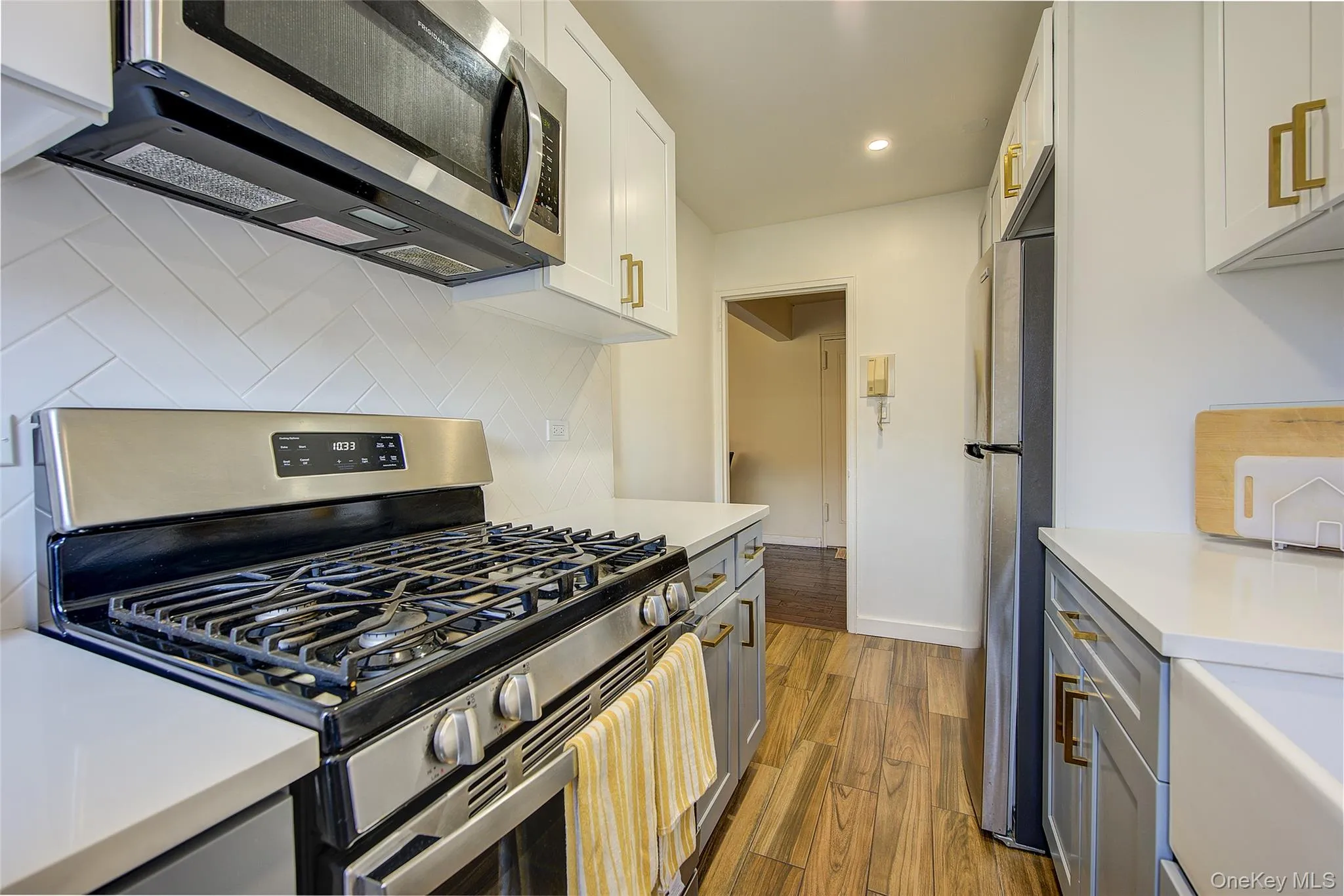 Kitchen featuring stainless steel appliances, decorative backsplash, light countertops, wood finished floors, and recessed lighting Kitchen featuring stainless steel appliances, decorative backsplash, light countertops, wood finished floors, and recessed lighting