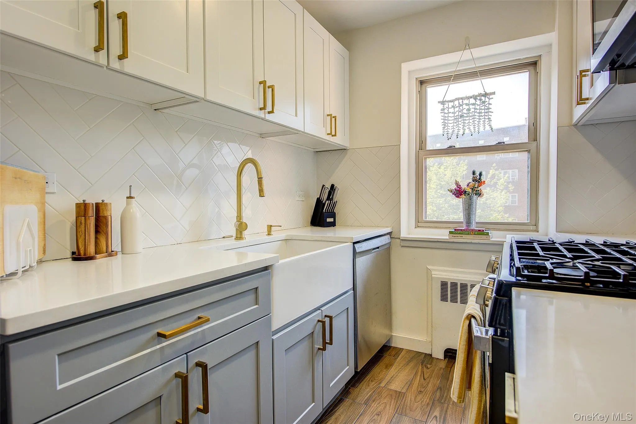 Kitchen featuring stainless steel appliances, gray cabinets, dark wood-style flooring, backsplash, and light countertops Kitchen featuring stainless steel appliances, gray cabinets, dark wood-style flooring, backsplash, and light countertops