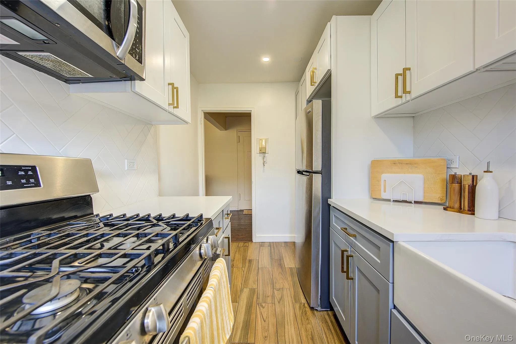 Kitchen featuring stainless steel appliances, light wood-style floors, decorative backsplash, recessed lighting, and light countertops Kitchen featuring stainless steel appliances, light wood-style floors, decorative backsplash, recessed lighting, and light countertops