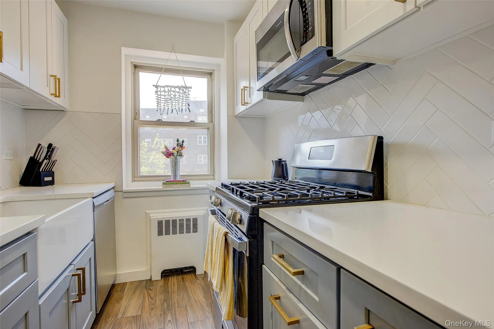 Kitchen with appliances with stainless steel finishes, radiator, backsplash, and light wood-style flooring Kitchen with appliances with stainless steel finishes, radiator, backsplash, and light wood-style flooring