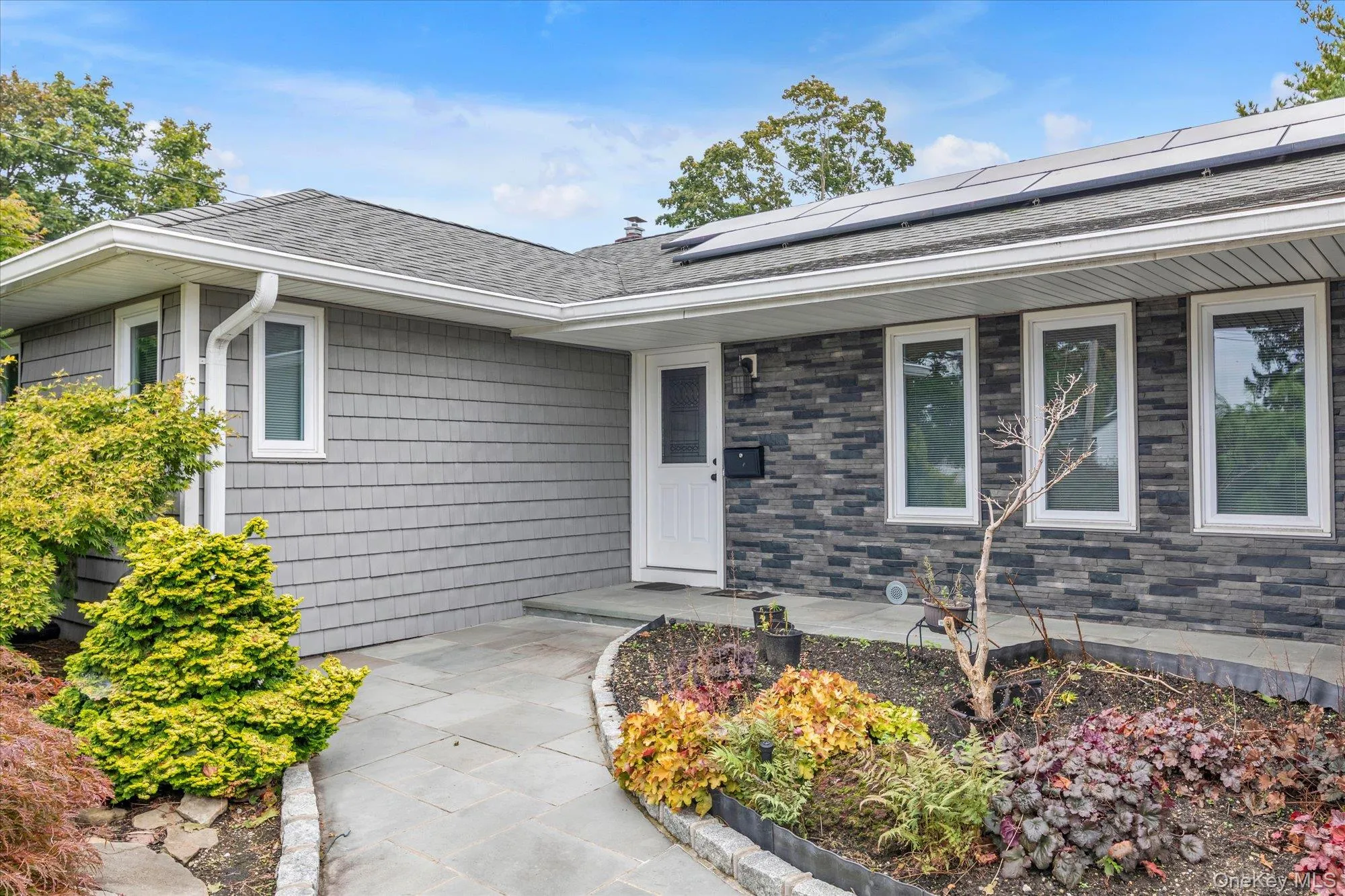 Gray shake siding exterior with dark stone accents, white window frames, and sitting area Gray shake siding exterior with dark stone accents, white window frames, and sitting area