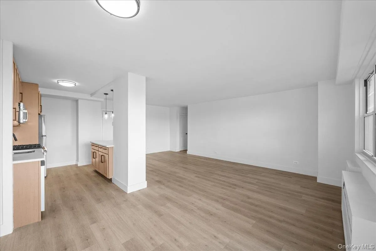 Open-concept living space with light vinyl flooring, and white walls Open-concept living space with light vinyl flooring, and white walls