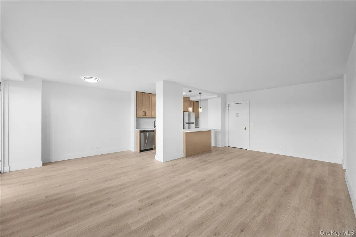 Open-concept living space with light vinyl flooring, and white walls Open-concept living space with light vinyl flooring, and white walls
