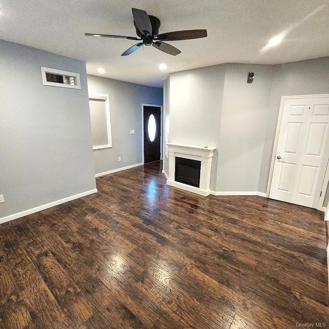 Expansive wood-finish flooring, recessed lighting, and a contemporary ceiling fan, with modern fireplace for family gathers and comfortable living Expansive wood-finish flooring, recessed lighting, and a contemporary ceiling fan, with modern fireplace for family gathers and comfortable living