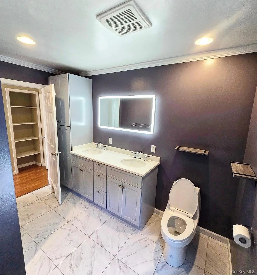 Dual vanity with undermount sinks, illuminated mirror, and integrated storage cabinetry Dual vanity with undermount sinks, illuminated mirror, and integrated storage cabinetry