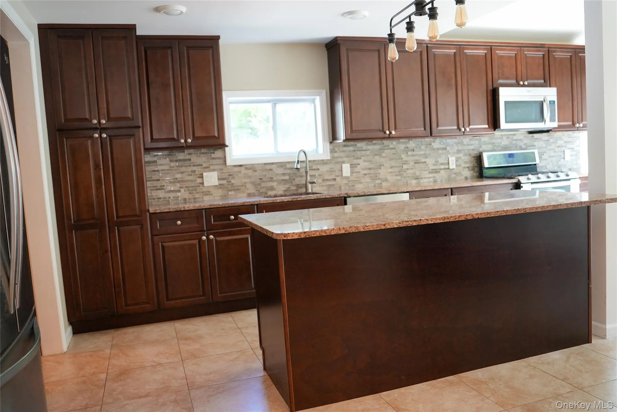Kitchen featuring dark wood-finish cabinetry, light-toned tile flooring, and a stone-finish countertop Kitchen featuring dark wood-finish cabinetry, light-toned tile flooring, and a stone-finish countertop