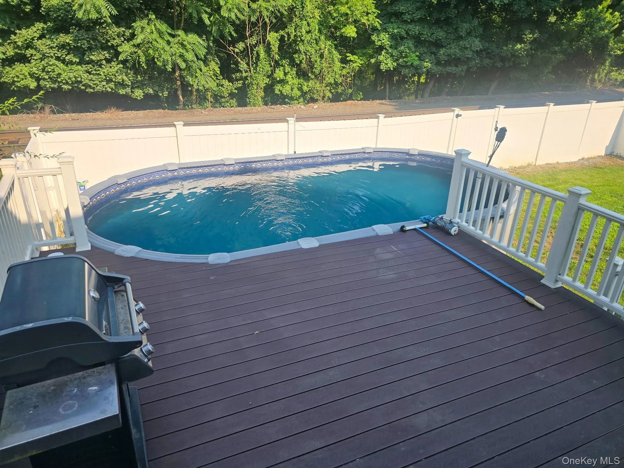 Expansive deck with an above-ground pool, composite decking, and white railing Expansive deck with an above-ground pool, composite decking, and white railing