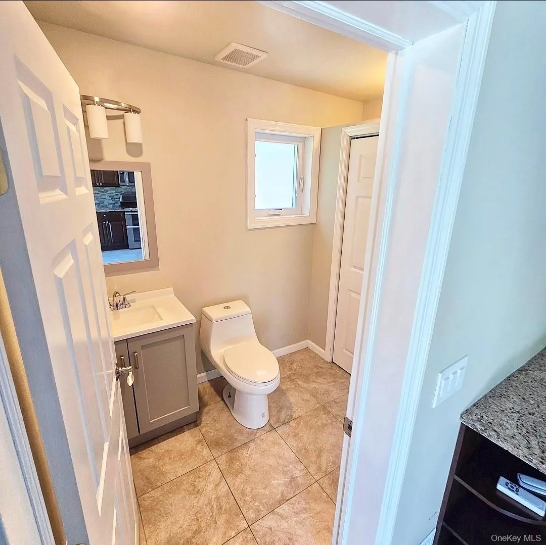 Bathroom featuring a compact vanity with an integrated sink, a contemporary toilet, and tiled flooring Bathroom featuring a compact vanity with an integrated sink, a contemporary toilet, and tiled flooring