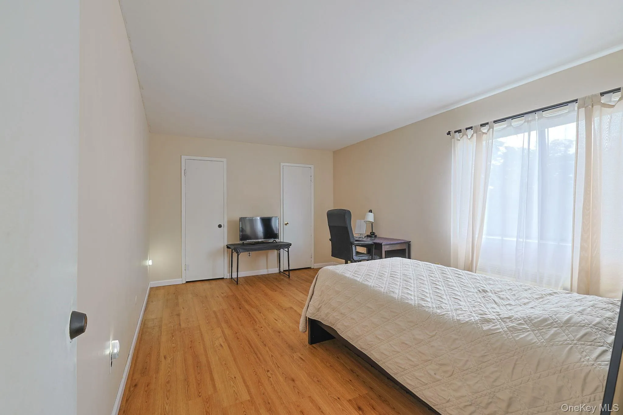 Primary bedroom featuring wood-finish flooring and duel walk in closets Primary bedroom featuring wood-finish flooring and duel walk in closets