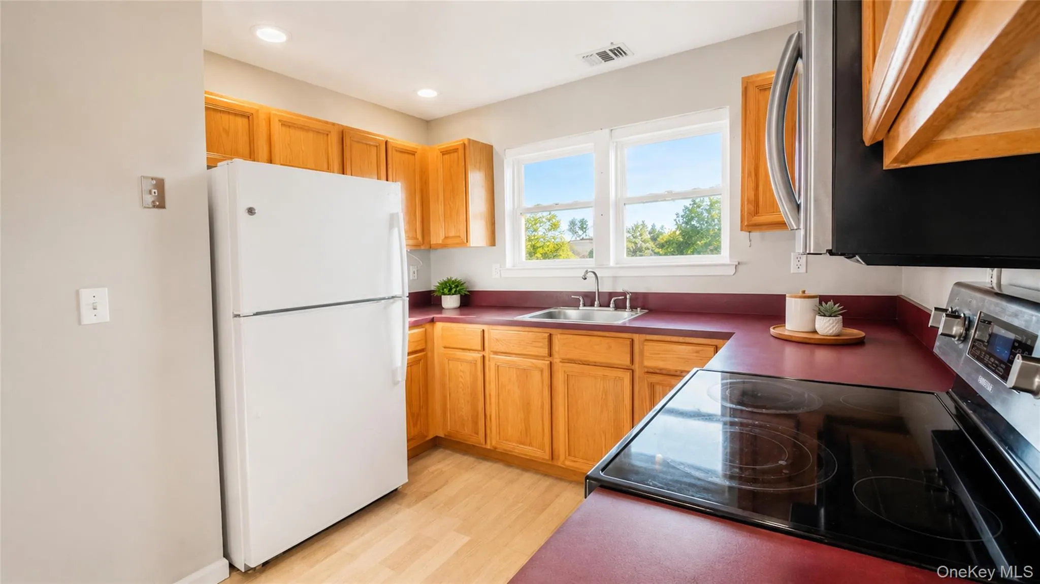 Sun-filled kitchen showcasing ample storage, expansive preparation space, and windows overlooking the surrounding greenery. Sun-filled kitchen showcasing ample storage, expansive preparation space, and windows overlooking the surrounding greenery.