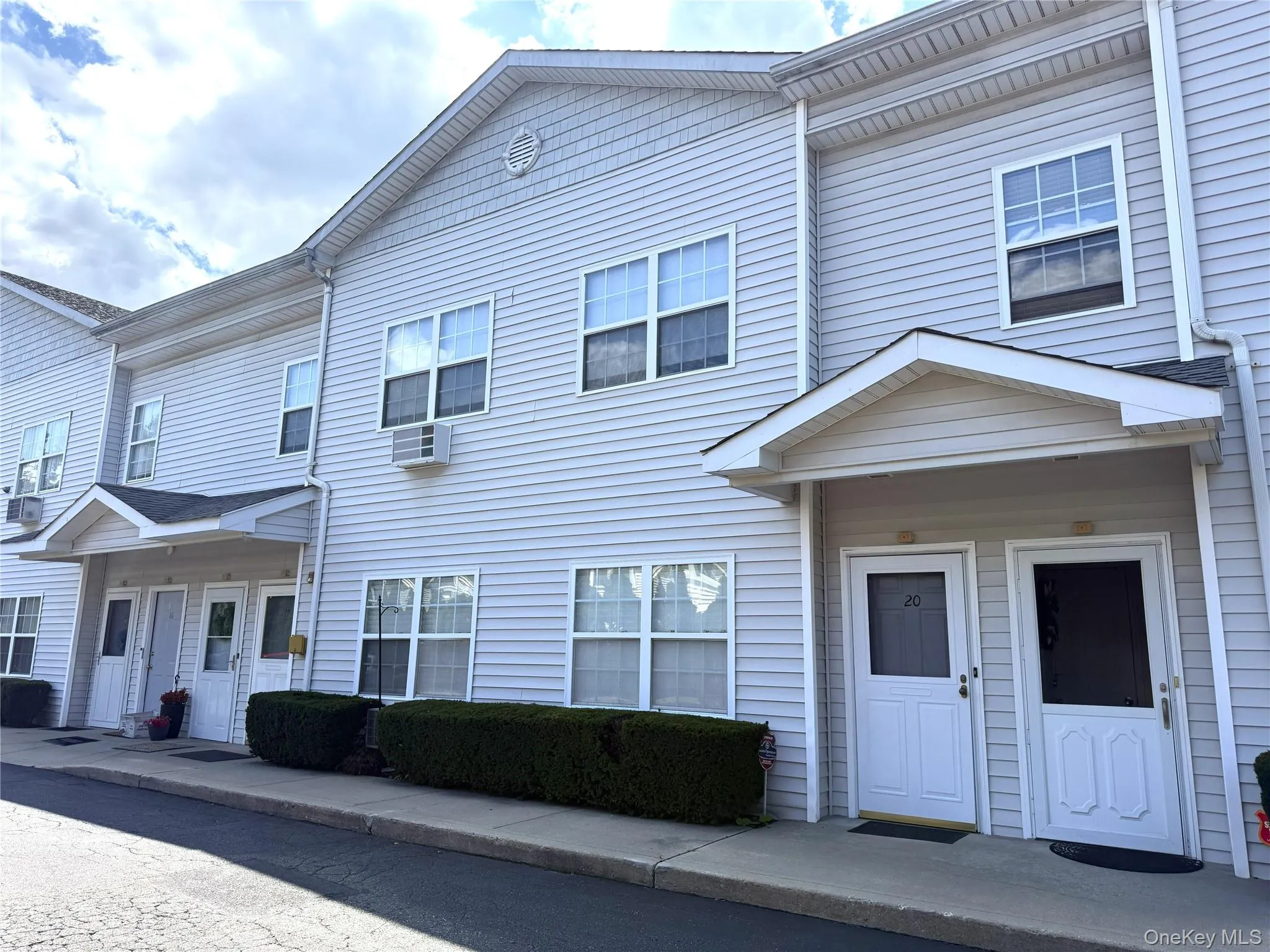 Multi-unit building featuring light-colored siding and individual entryways with covered porches Multi-unit building featuring light-colored siding and individual entryways with covered porches