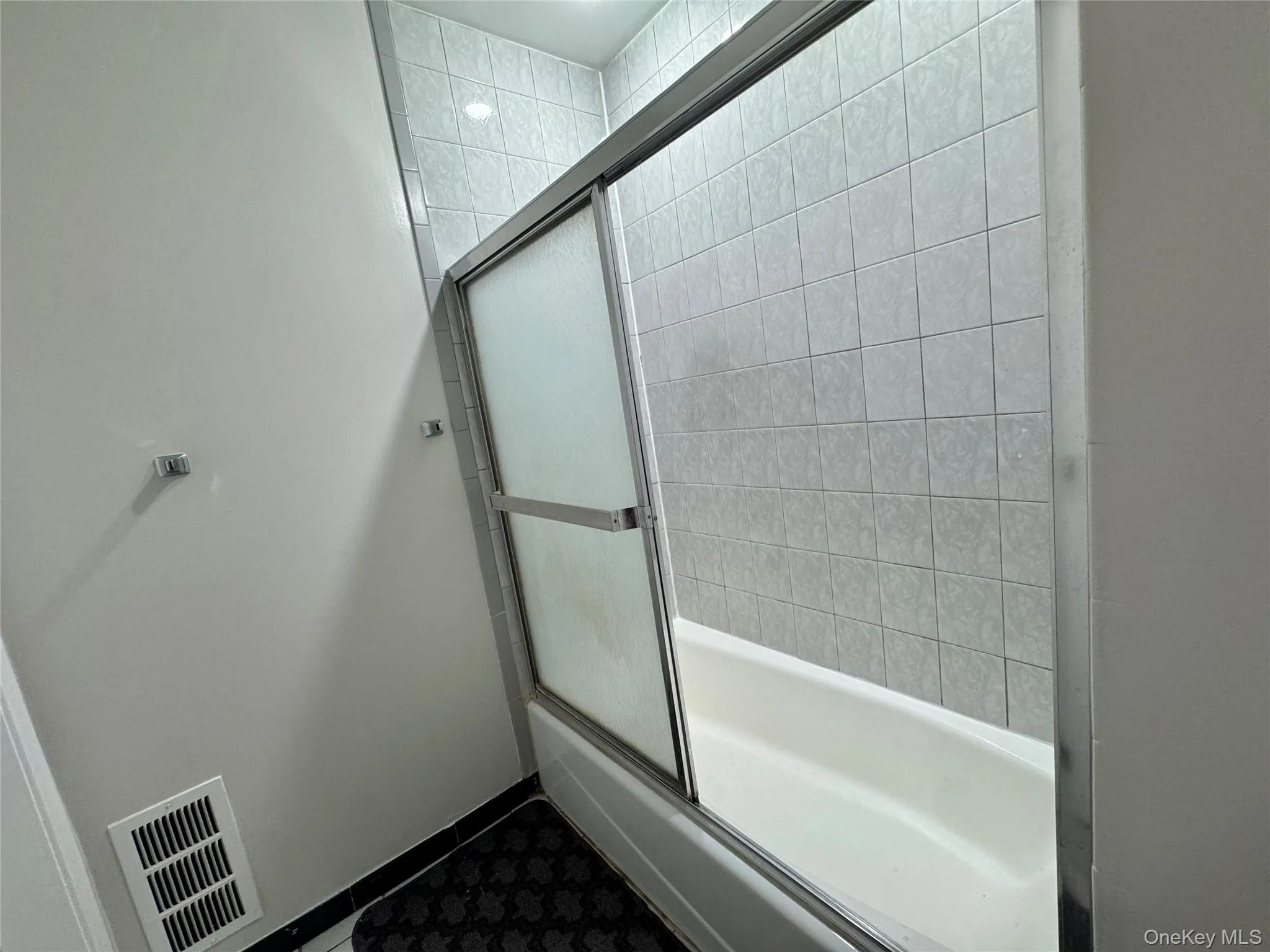 Bathtub with sliding frosted glass enclosure and tile surround Bathtub with sliding frosted glass enclosure and tile surround