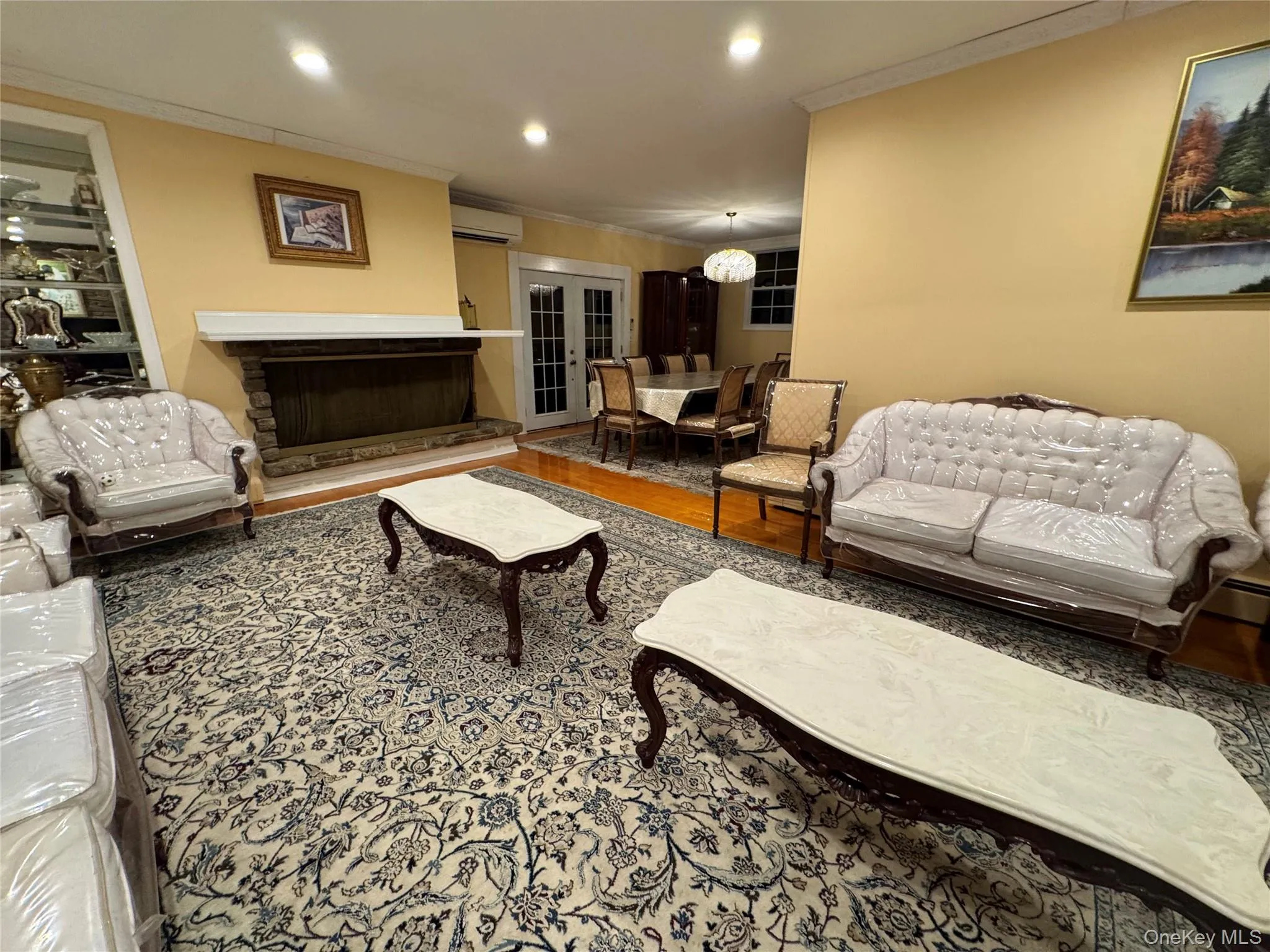 Stone-clad fireplace with a white mantel, recessed lighting, and hardwood flooring Stone-clad fireplace with a white mantel, recessed lighting, and hardwood flooring