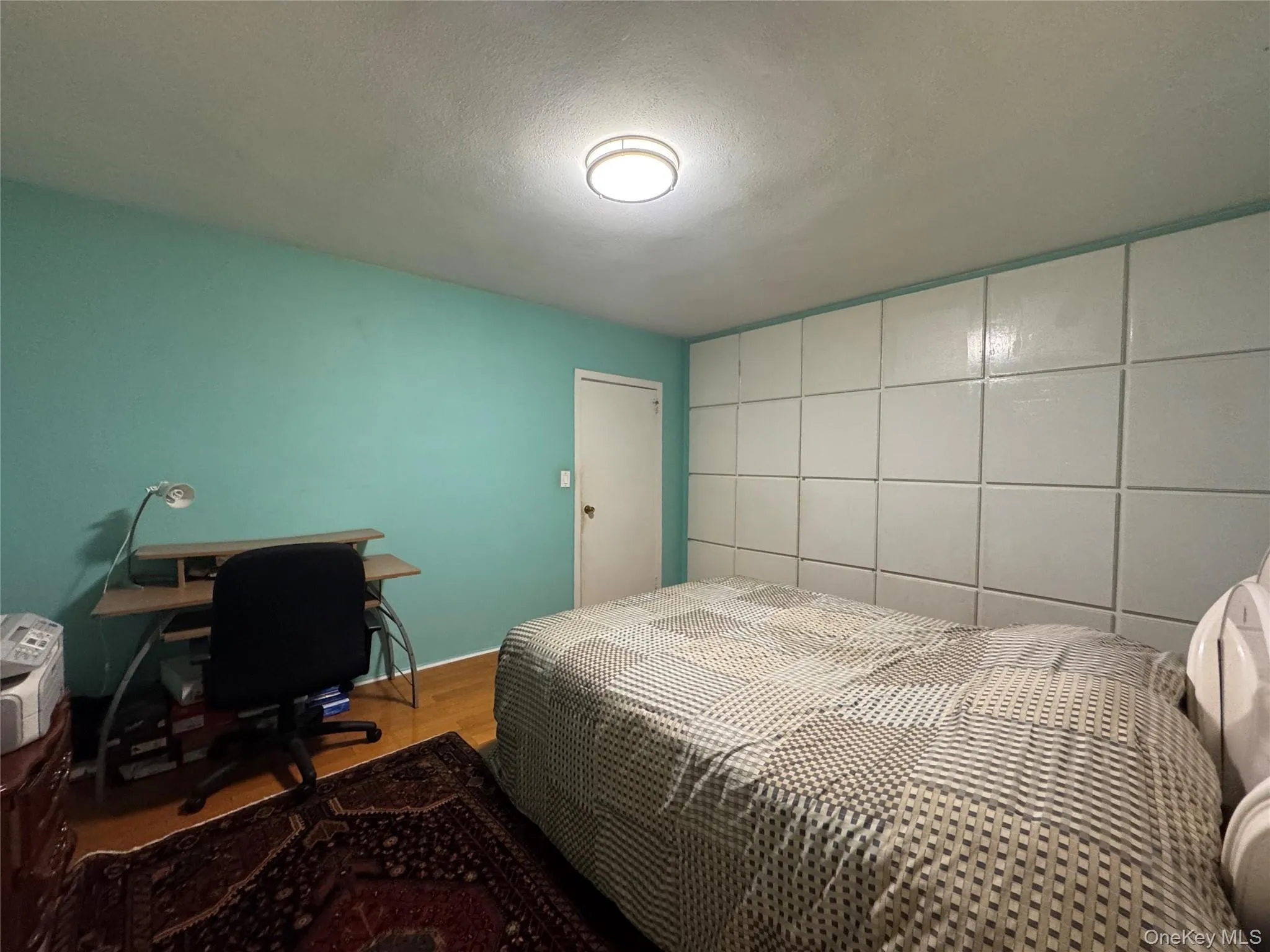 Wood-finish flooring with a textured ceiling and a flush-mount light fixture Wood-finish flooring with a textured ceiling and a flush-mount light fixture