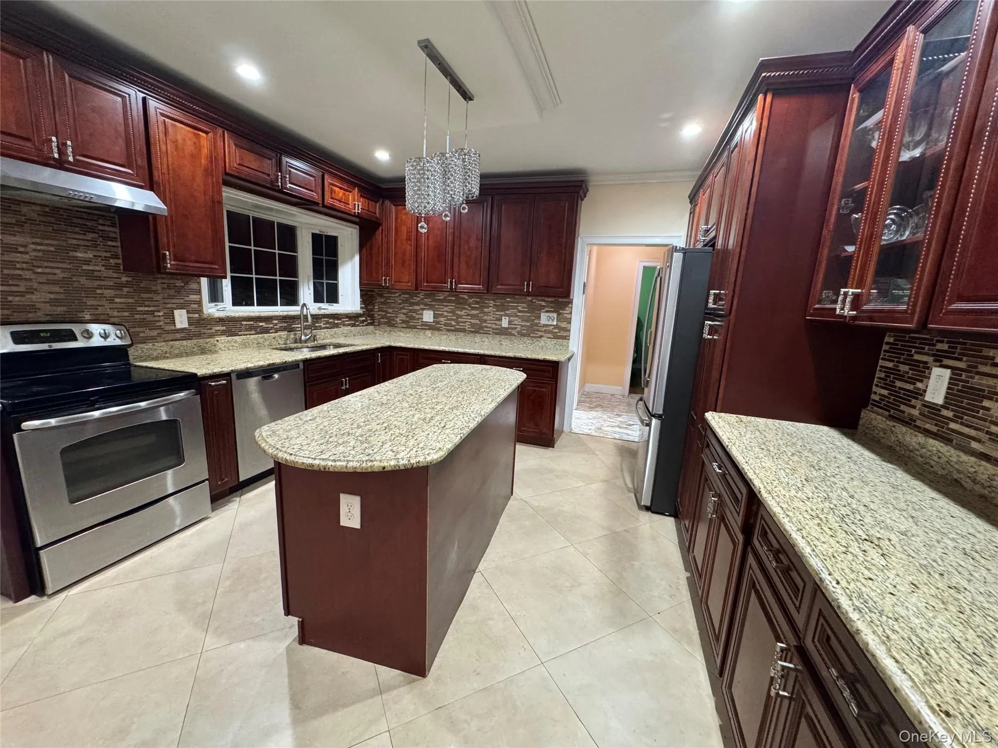 Cherry wood-finish cabinetry with glass-front accents, stainless steel appliances, granite countertops, and a central island Cherry wood-finish cabinetry with glass-front accents, stainless steel appliances, granite countertops, and a central island