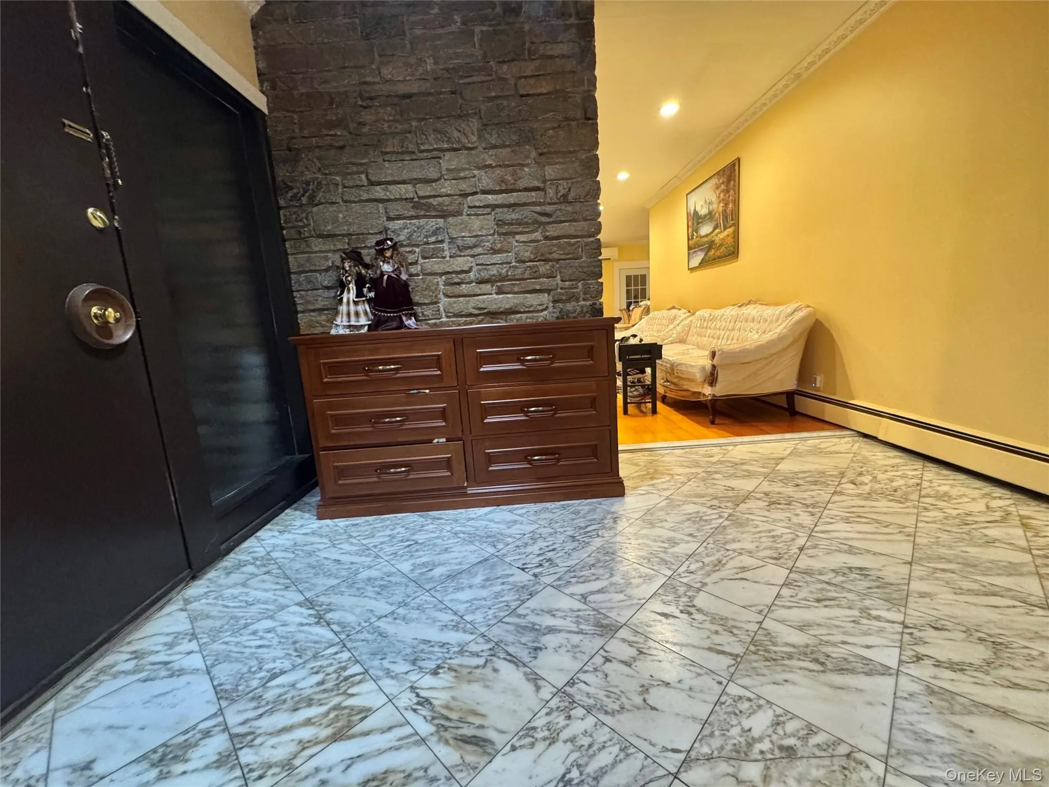 Entryway featuring stone-look accent wall, marble-look tile flooring, and crown molding Entryway featuring stone-look accent wall, marble-look tile flooring, and crown molding