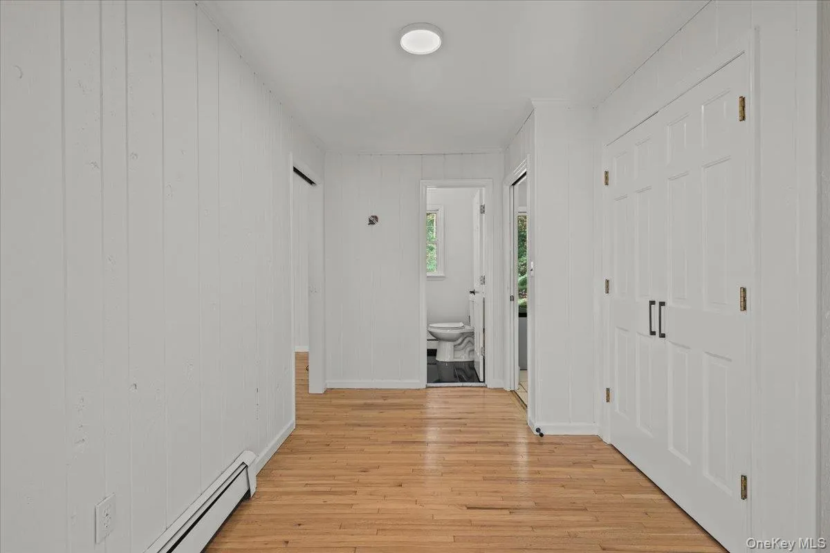 Hardwood flooring, painted paneled walls, white panel doors with black hardware, and an overhead flush-mount light fixture Hardwood flooring, painted paneled walls, white panel doors with black hardware, and an overhead flush-mount light fixture