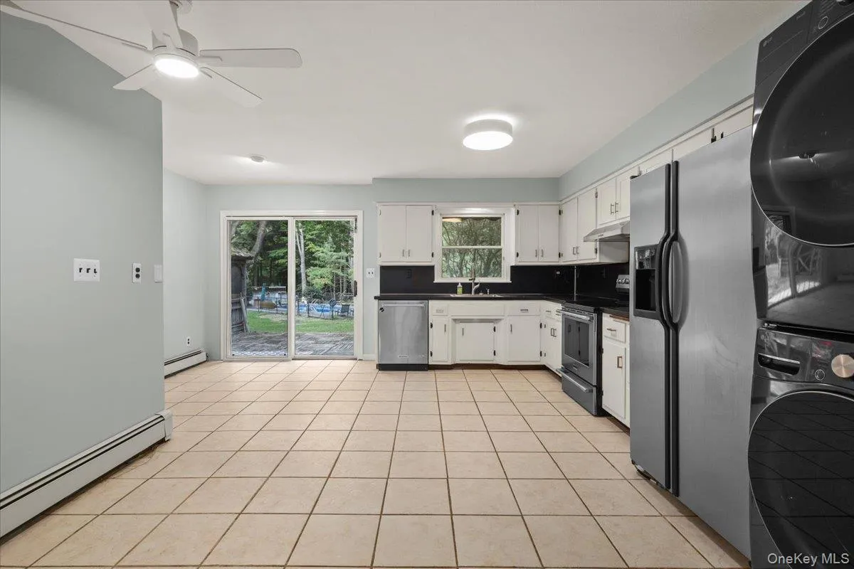 Spacious kitchen area featuring tile flooring, white cabinetry, integrated stainless steel appliances, and a ceiling fan Spacious kitchen area featuring tile flooring, white cabinetry, integrated stainless steel appliances, and a ceiling fan