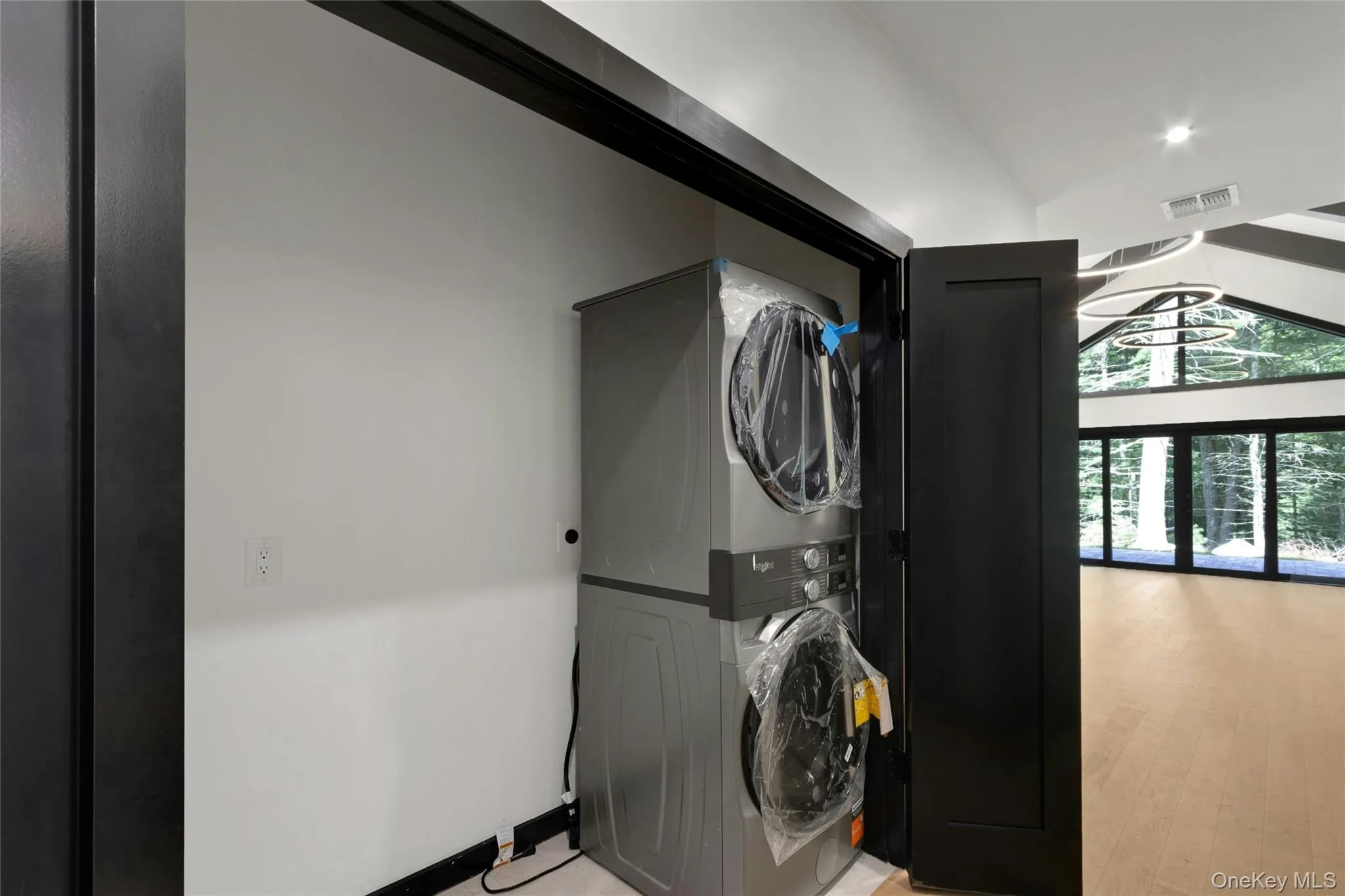 Stacked washer and dryer unit, recessed lighting, vaulted ceilings, and a wood-finish floor Stacked washer and dryer unit, recessed lighting, vaulted ceilings, and a wood-finish floor