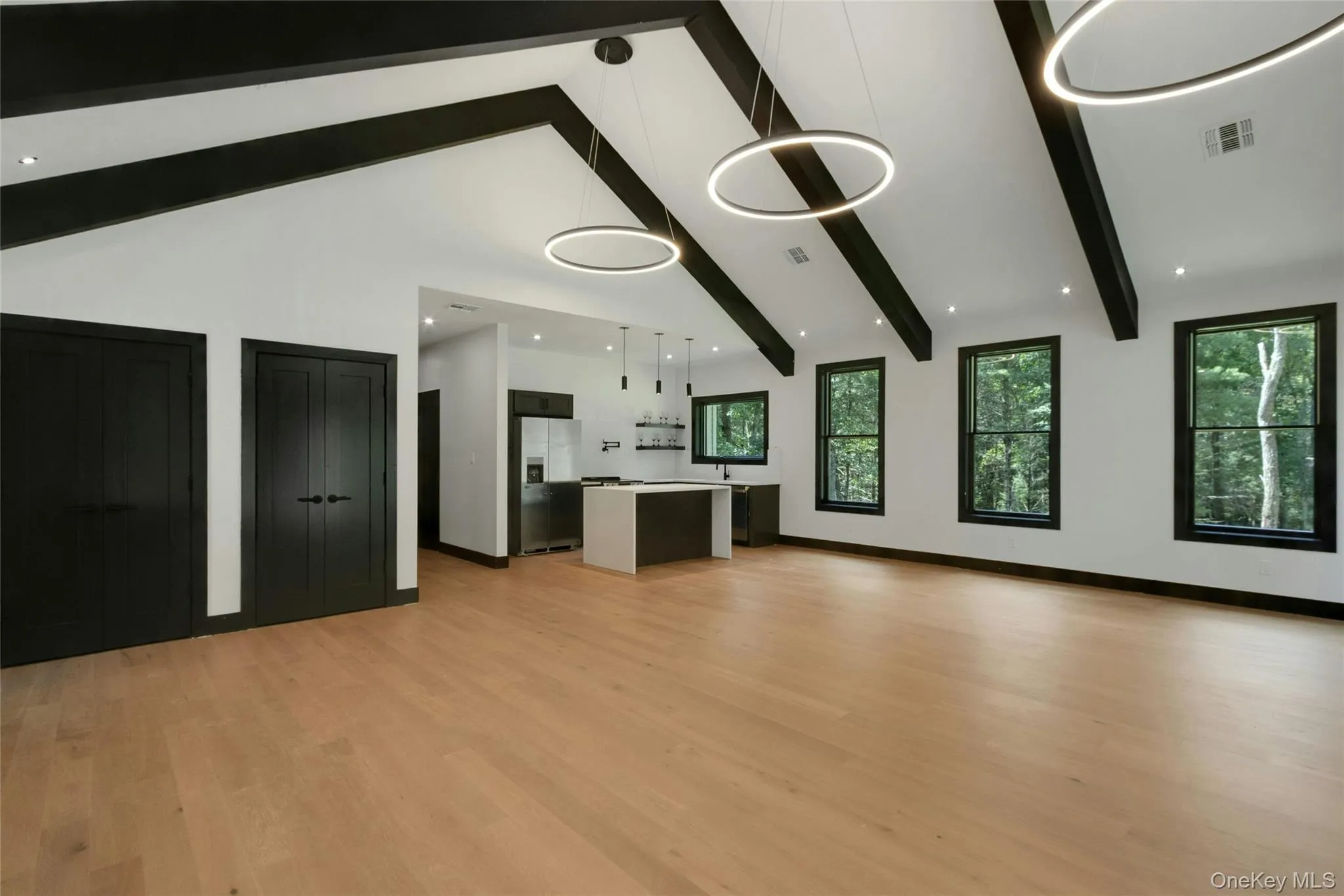 Vaulted ceiling with exposed beams, wood-finish flooring, recessed lighting, contemporary pendant lighting, and multiple windows Vaulted ceiling with exposed beams, wood-finish flooring, recessed lighting, contemporary pendant lighting, and multiple windows
