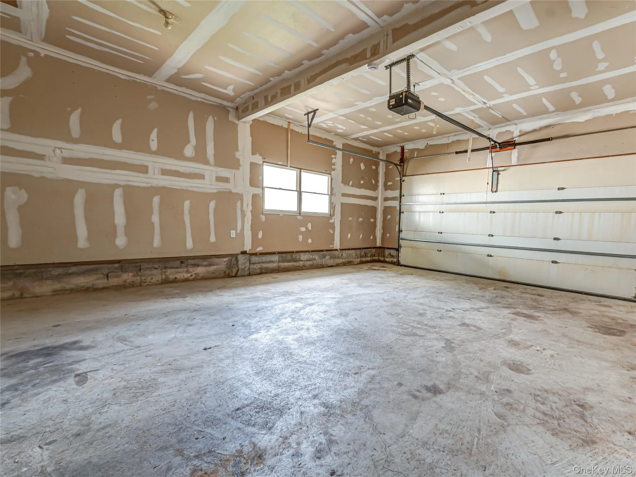 Two-car garage with a concrete floor, automatic garage door opener, and natural light from a window Two-car garage with a concrete floor, automatic garage door opener, and natural light from a window