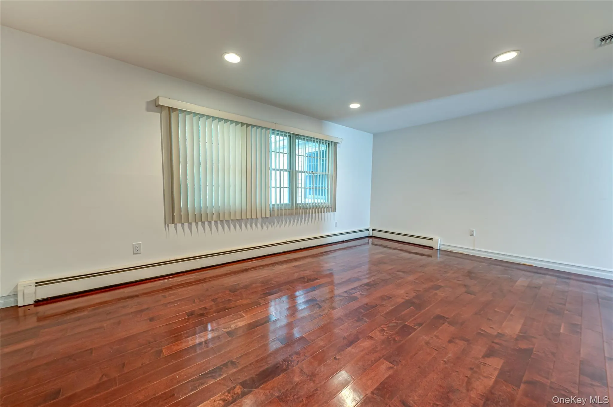 Rich wood-finish flooring, white walls, recessed ceiling lighting, and a window with blinds Rich wood-finish flooring, white walls, recessed ceiling lighting, and a window with blinds