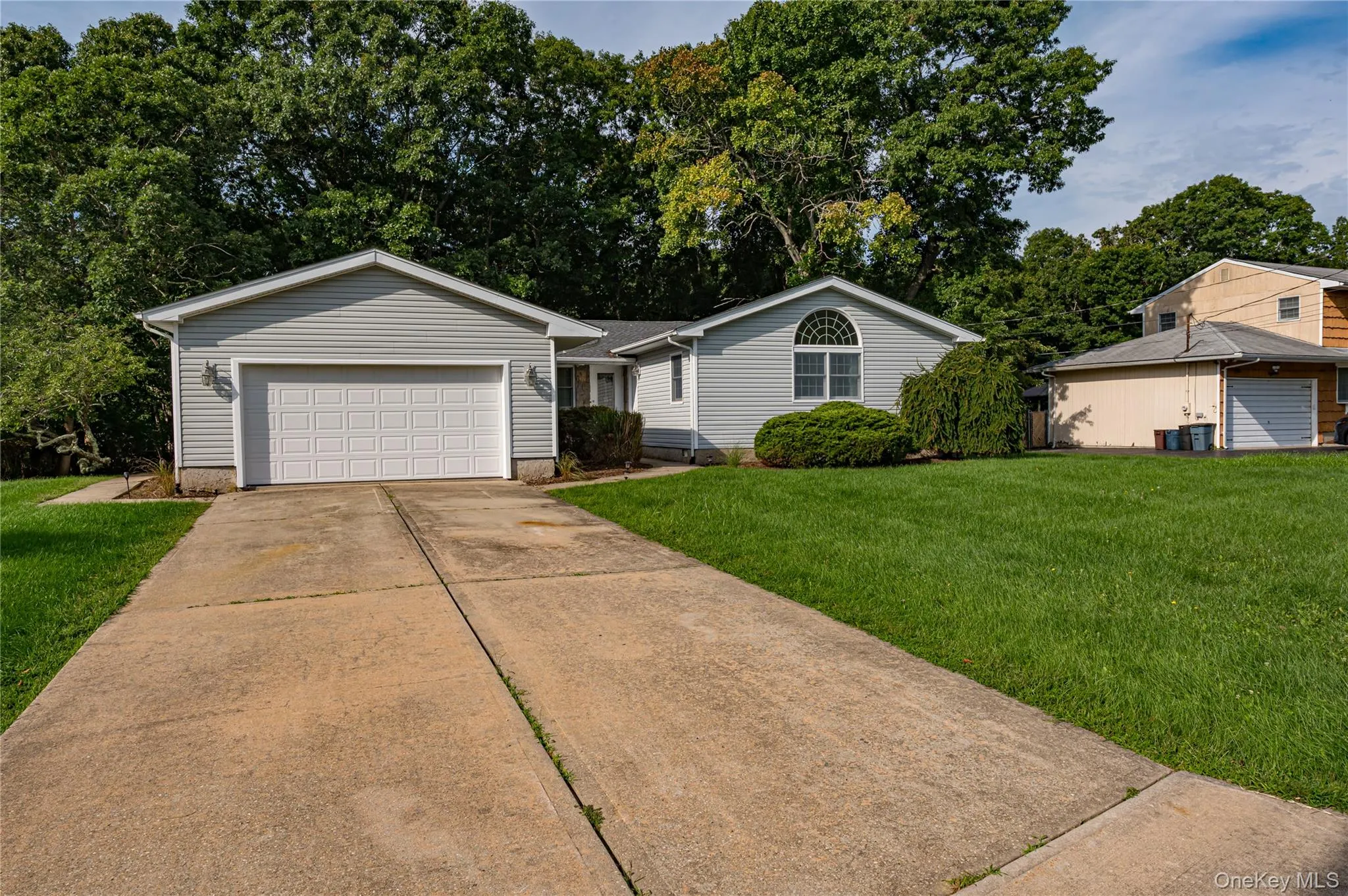 Light gray siding exterior with a two-car garage, concrete driveway, and a manicured front lawn Light gray siding exterior with a two-car garage, concrete driveway, and a manicured front lawn