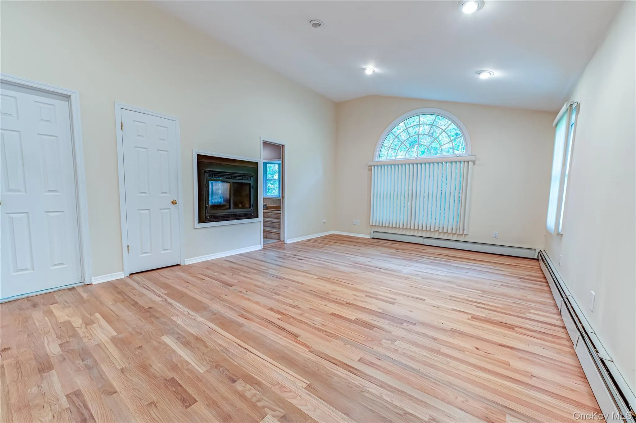 Vaulted ceiling, recessed lighting, wood-finish flooring, double sided fireplace, and arched window Vaulted ceiling, recessed lighting, wood-finish flooring, double sided fireplace, and arched window