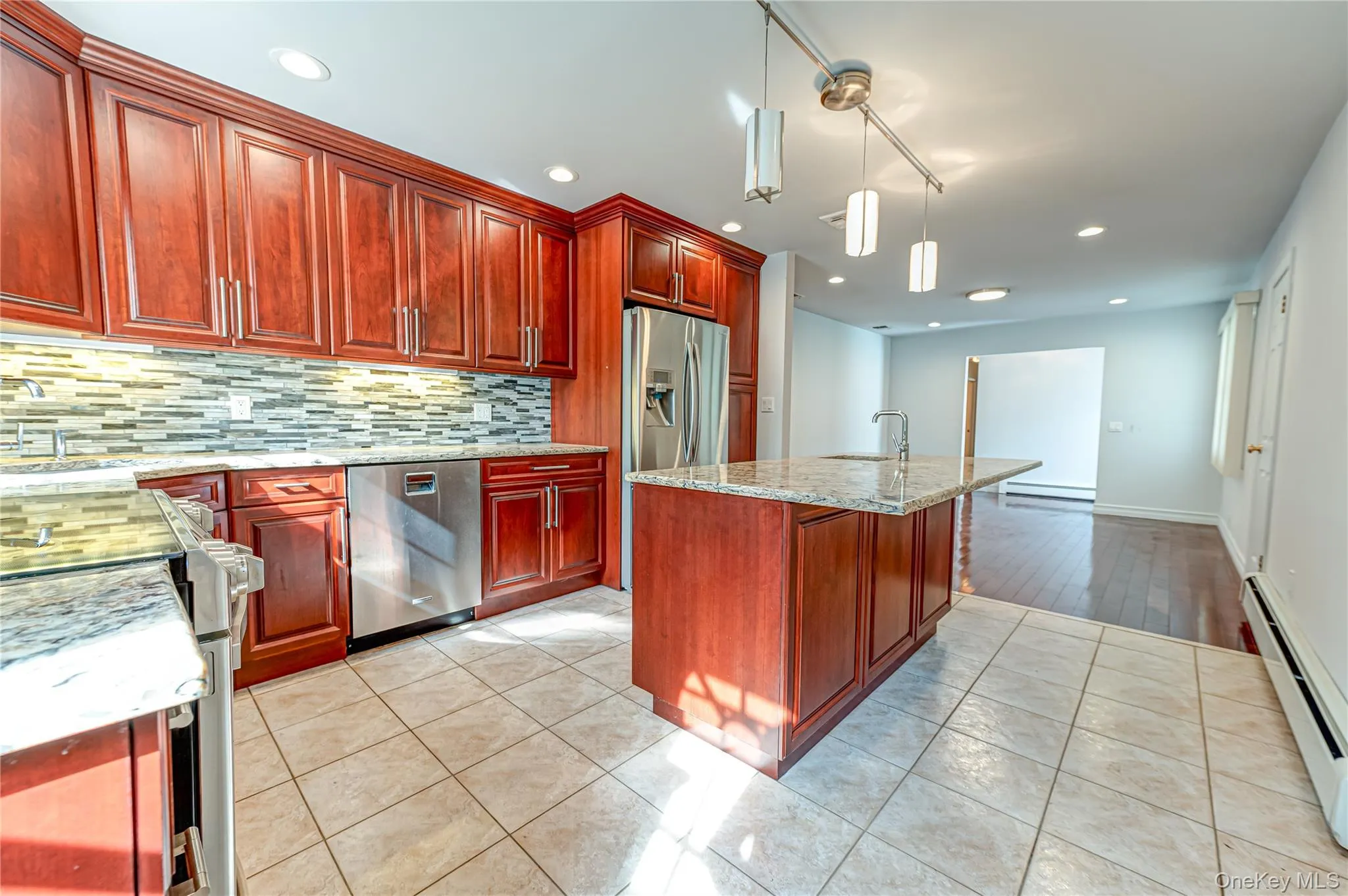 Kitchen featuring wood cabinetry, stainless steel appliances, a center island with sink, tile flooring, and recessed lighting Kitchen featuring wood cabinetry, stainless steel appliances, a center island with sink, tile flooring, and recessed lighting