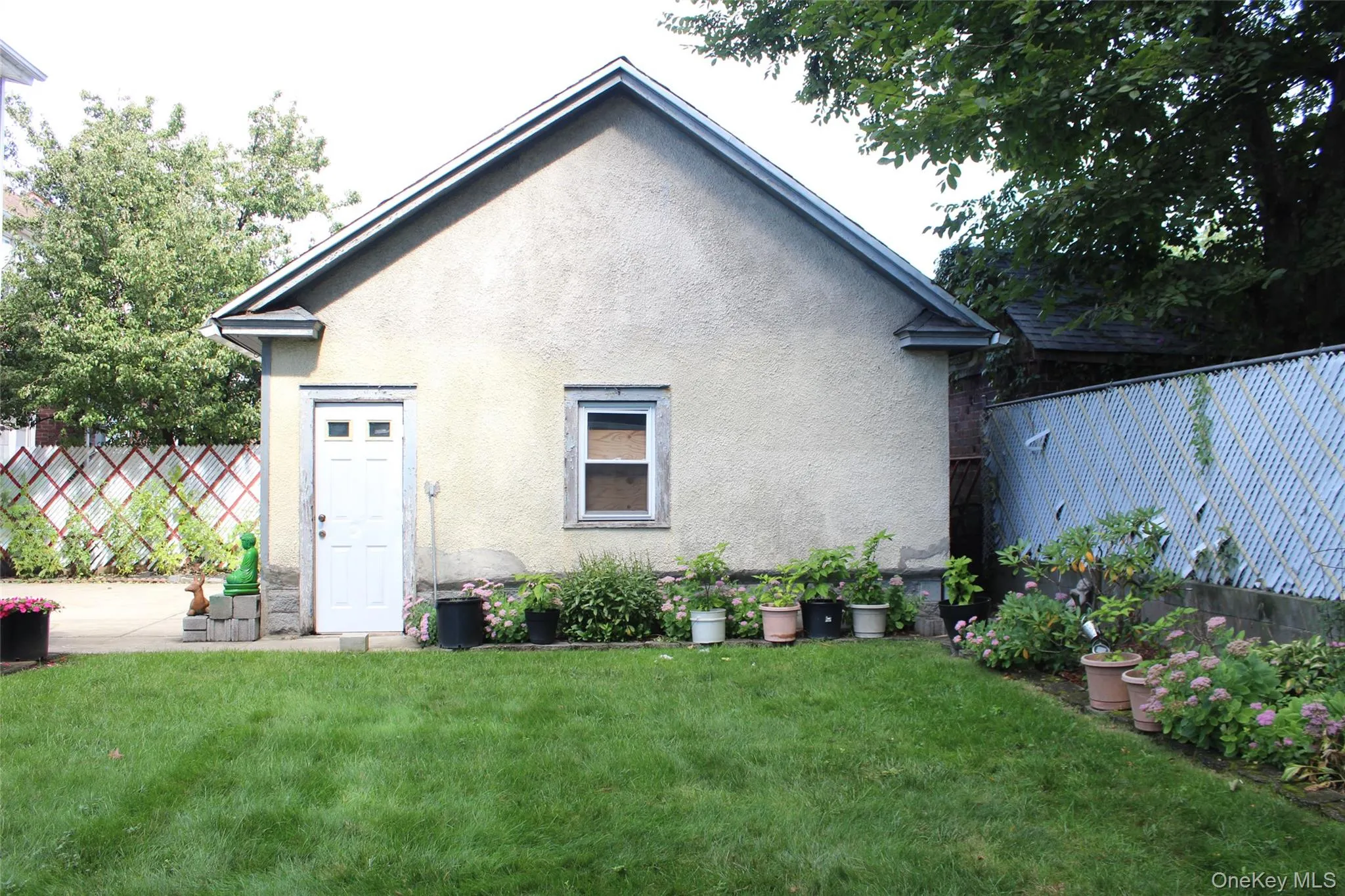 Stucco exterior with a gable roof, featuring a white door and a single window Stucco exterior with a gable roof, featuring a white door and a single window