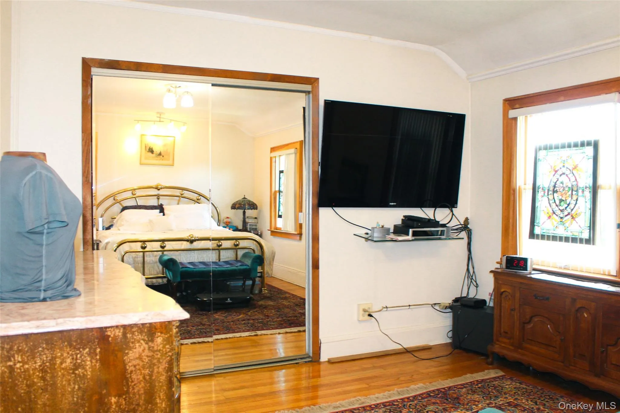 Bedroom 1 has hardwood flooring, crown molding, and a stained glass window detail with large closet Bedroom 1 has hardwood flooring, crown molding, and a stained glass window detail with large closet