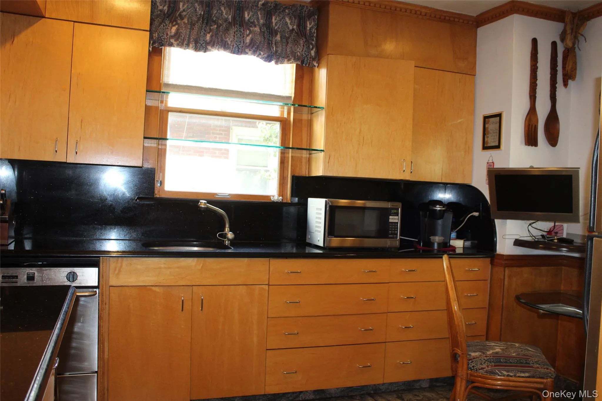 Birch wood cabinetry with built-in dishwasher, and a window with glass shelving Birch wood cabinetry with built-in dishwasher, and a window with glass shelving