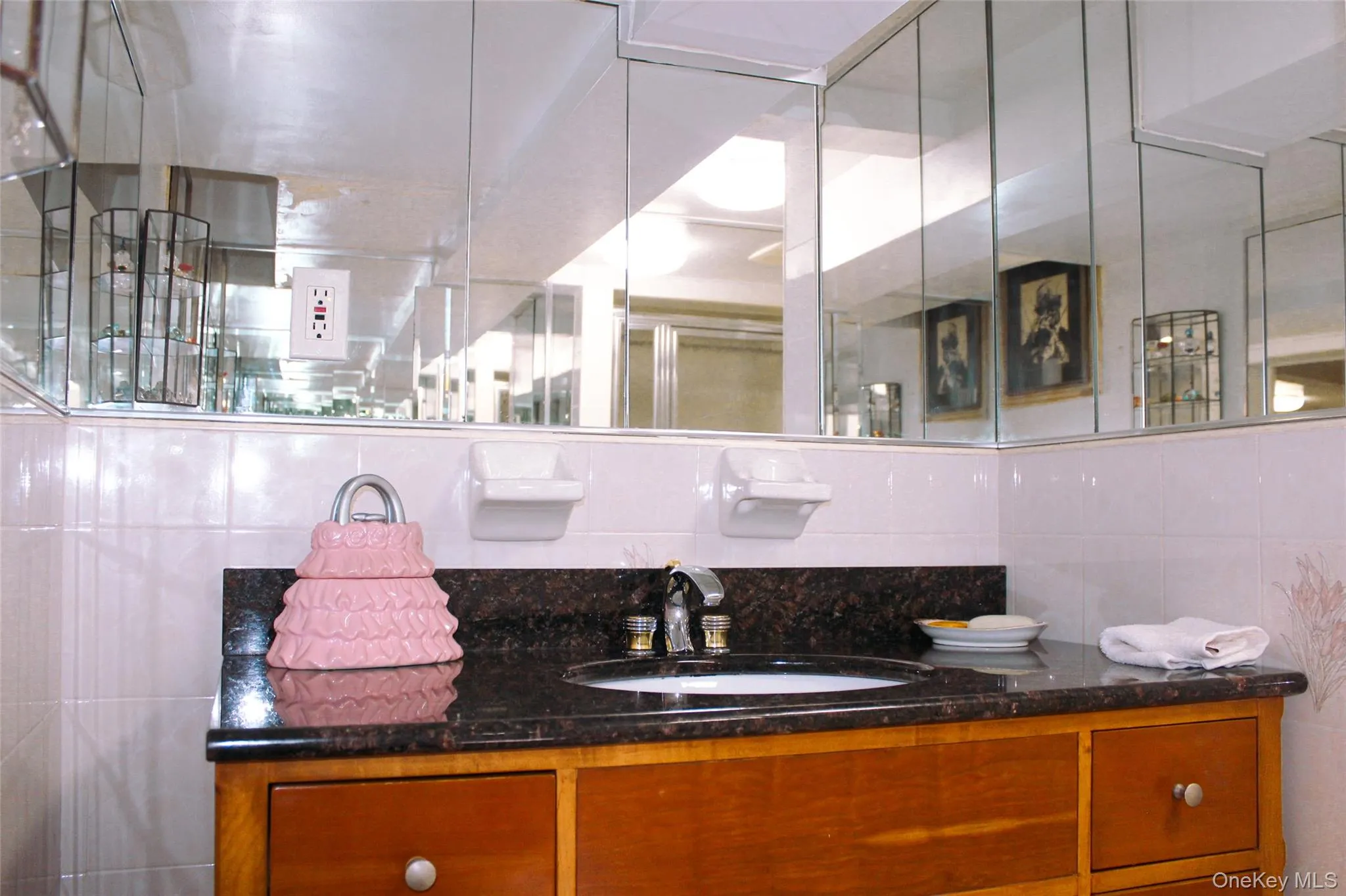 Basement bathroom with wood-finish vanity with drawer storage, dark stone-finish countertop, and a built-in sink basin Basement bathroom with wood-finish vanity with drawer storage, dark stone-finish countertop, and a built-in sink basin