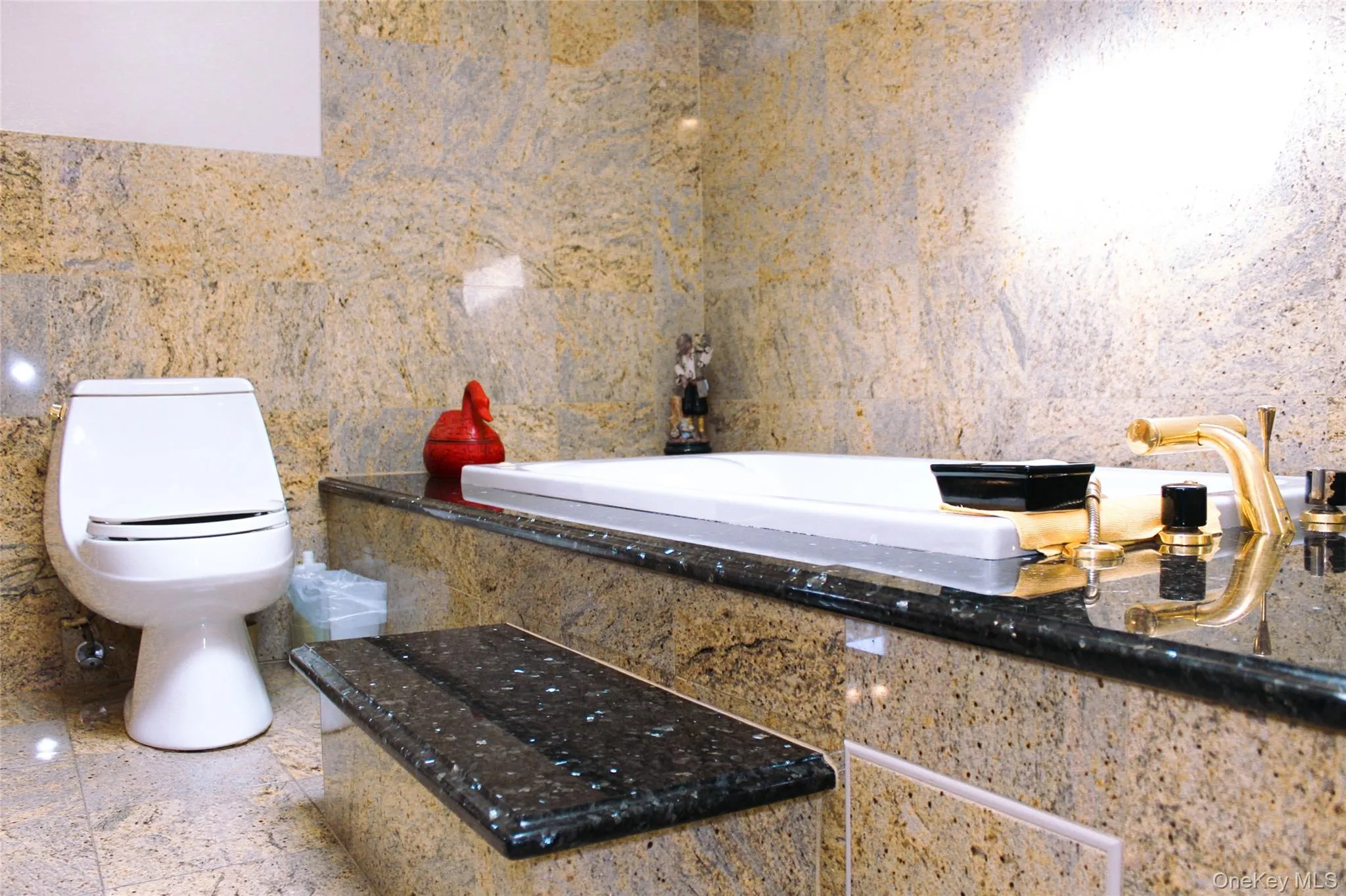 2nd floor bathroom has built-in soaking tub, tile flooring, wall-mounted oval mirror, wood cabinetry with polished hardware, and stone countertops 2nd floor bathroom has built-in soaking tub, tile flooring, wall-mounted oval mirror, wood cabinetry with polished hardware, and stone countertops