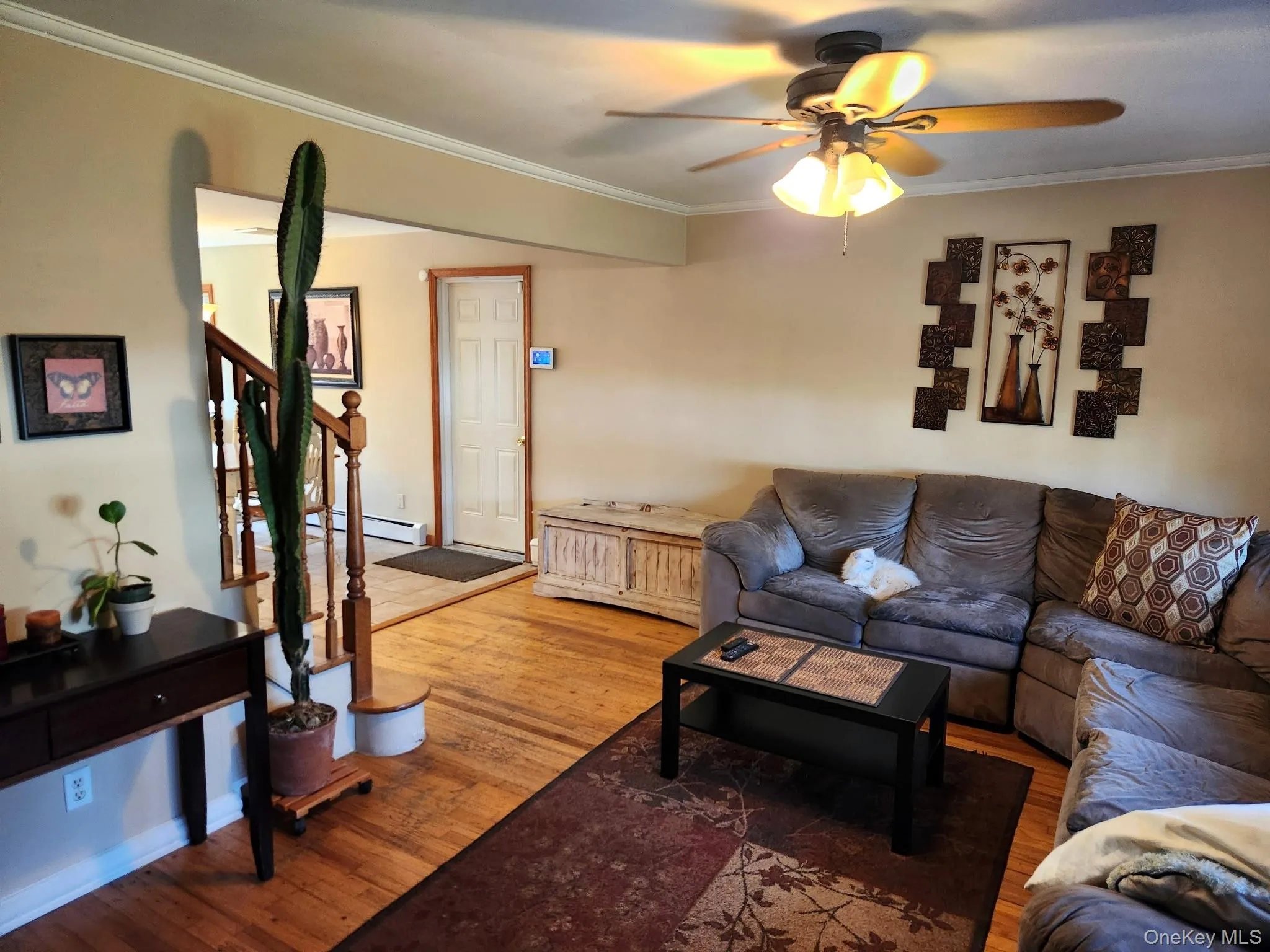 Hardwood flooring, painted walls, crown molding, ceiling fan with integrated lighting, and a staircase with wood railings Hardwood flooring, painted walls, crown molding, ceiling fan with integrated lighting, and a staircase with wood railings