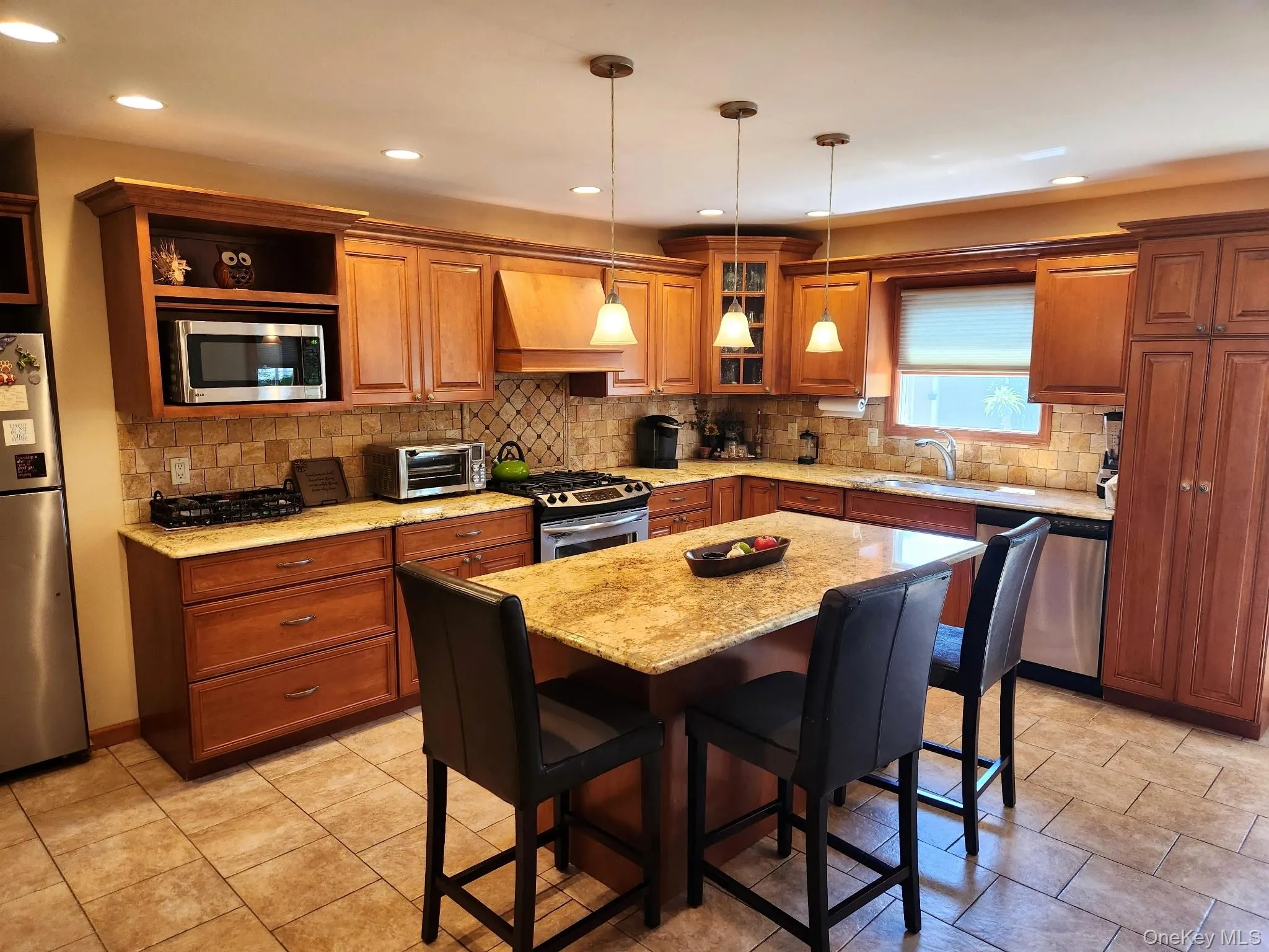 Wood-finish cabinetry with crown molding, stainless steel appliances, stone countertops, tiled backsplash, and recessed lighting Wood-finish cabinetry with crown molding, stainless steel appliances, stone countertops, tiled backsplash, and recessed lighting